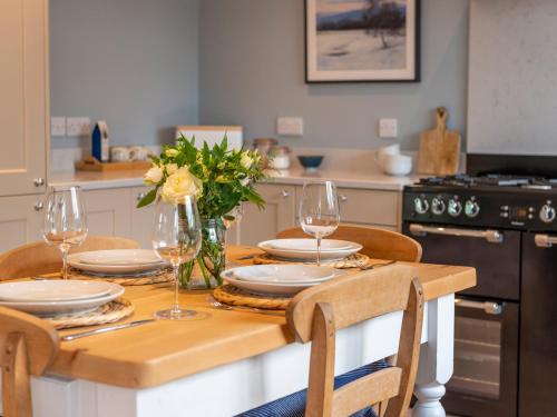 a dining room table with glasses and flowers on it at Walton House Cottage in Chapel en le Frith