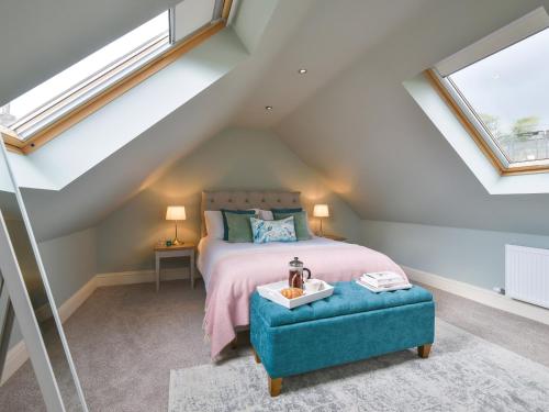 a attic bedroom with a bed and a blue ottoman at Walton House Cottage in Chapel en le Frith