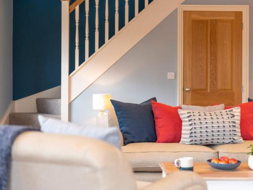 a living room with a couch with red and blue pillows at Walton House Cottage in Chapel en le Frith