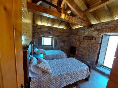 duas camas num quarto com uma parede de pedra em Casa Guardião do Castelo em Celorico de Basto