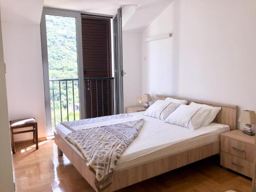 1 dormitorio con 1 cama grande y balcón en Lavender Bay Apartment D9, en Donji Morinj