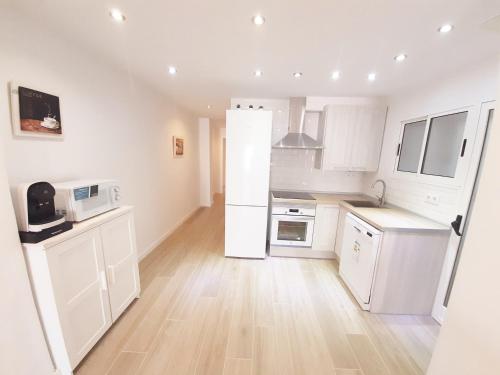 a kitchen with white appliances and a wooden floor at Tarragonaapartments Prim Reus in Reus