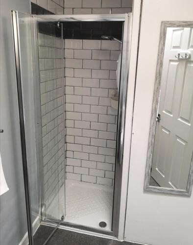 a shower with a glass door and a mirror at The Sunfold in Weston-super-Mare