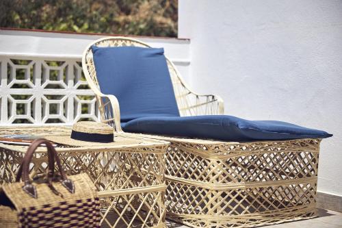 a wicker chair with a blue pillow and a basket at Casas Sul in Burgau