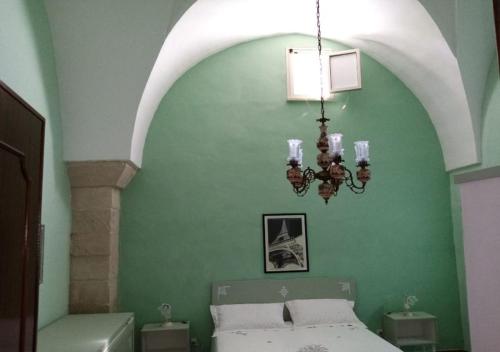 een slaapkamer met een groene muur en een kroonluchter bij DIMORA DI Vito in Nociglia