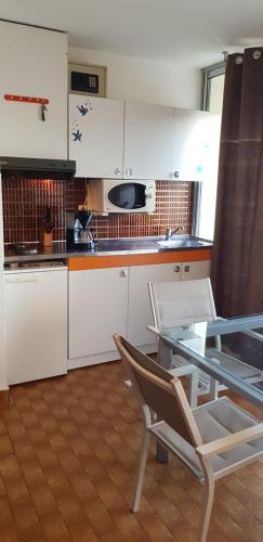 une cuisine avec des armoires blanches et une table et des chaises dans l'établissement Studio Naturiste 