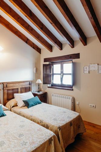 two beds in a room with wooden ceilings at El Acebo in Infiesto