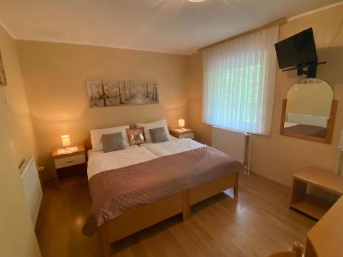 a bedroom with a bed with two lamps and a television at Guest House Golja in Bled