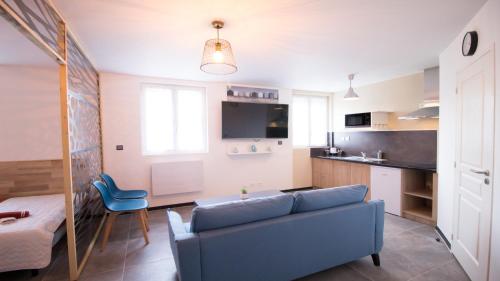 un salon avec un canapé bleu et une cuisine dans l'établissement Appartel 76 Dieppe, à Rouxmesnil-Bouteilles