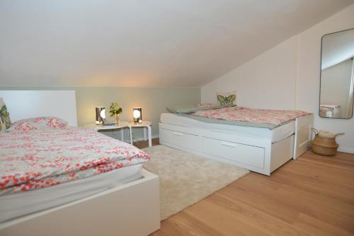 Un dormitorio blanco con dos camas y un espejo. en Ferienwohnung Innsbruck-Vill, en Innsbruck