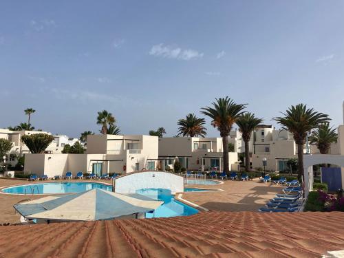a resort with a pool and palm trees and buildings at Alisios Dream in Corralejo