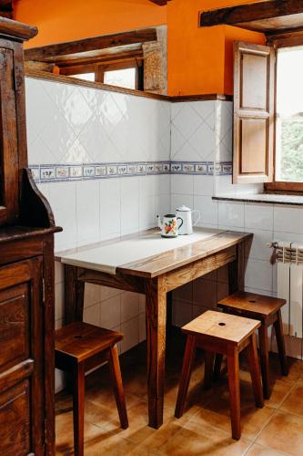 a kitchen with a wooden table and two stools at La Rectoral in Beloncio