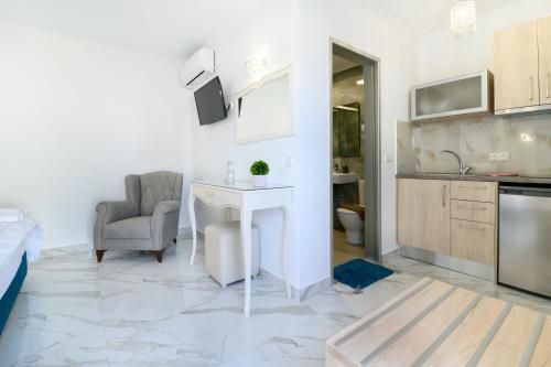 a white kitchen with a desk and a chair in a room at Sueño Suites in Parga