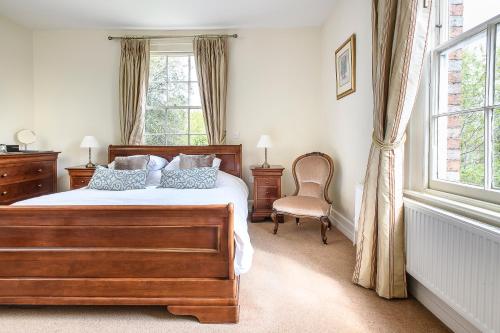 a bedroom with a bed and a chair and a window at Sissinghurst Castle Farmhouse in Sissinghurst