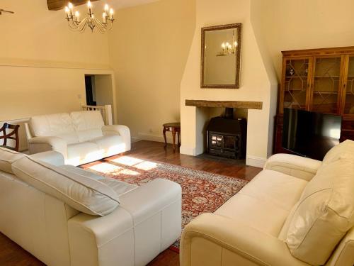 a living room with white furniture and a fireplace at Willow House in Hereford