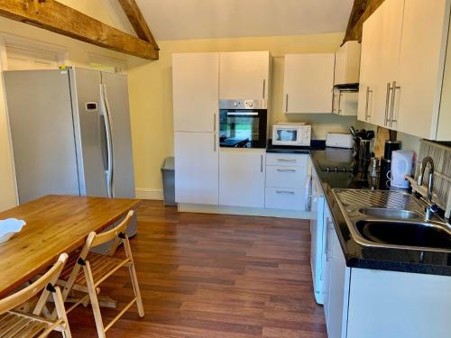 a kitchen with white cabinets and a wooden table at Willow House in Hereford