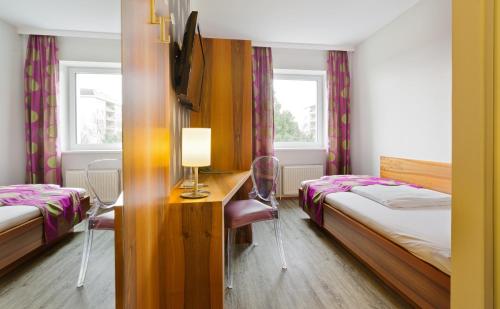 a bedroom with two beds and a desk with a lamp at Motel Baden in Baden