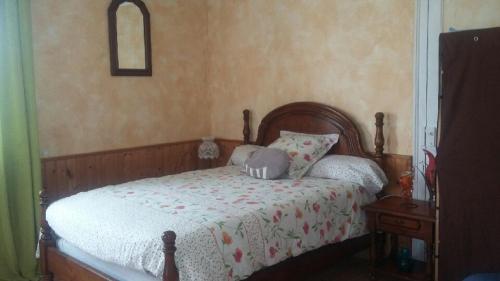 a bedroom with a wooden bed with a white comforter at MAISON MARTINOT in Samadet