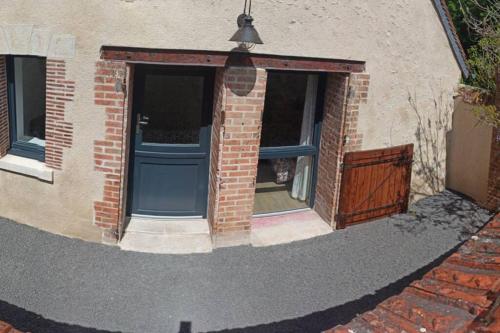 ein Backsteingebäude mit einer blauen Tür und einem Fenster in der Unterkunft Gîte Le Tico in Cheverny