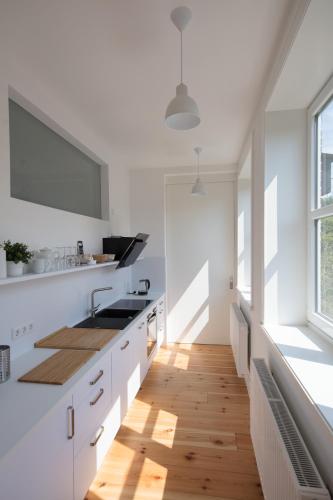 a kitchen with white cabinets and a wooden floor at Künstlerhaus in Niebüll