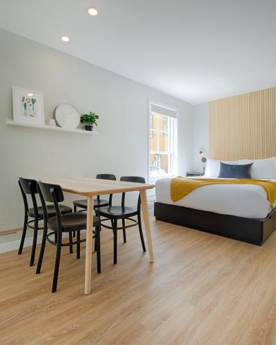 a bedroom with a bed and a table and chairs at Appart Hôtel Le Saint-Anselme - Par Revenus Locatifs Qc in Quebec City