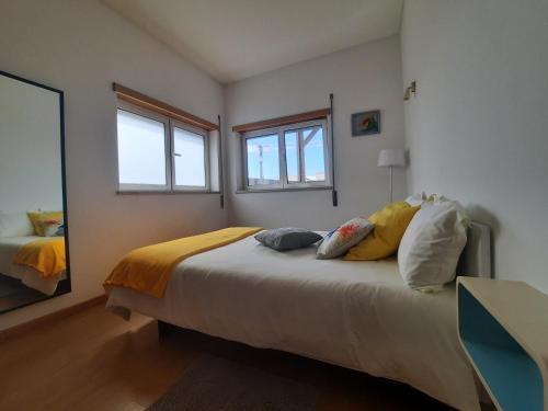 a bedroom with a bed with pillows and a mirror at Sunflower Sea View with magnificent terrace in Serra da Pescaria, Nazaré - Portugal in Nazaré