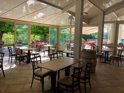 ein Restaurant mit Tischen, Stühlen und Fenstern in der Unterkunft Hotel Restaurant La Dame du Lac in Monflanquin