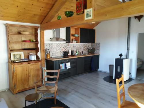 een keuken met zwarte kasten en een tafel en stoelen bij Charmante maison au coeur du Lavaux, Cully, cuisine, WiFi, Les Echalas in Cully
