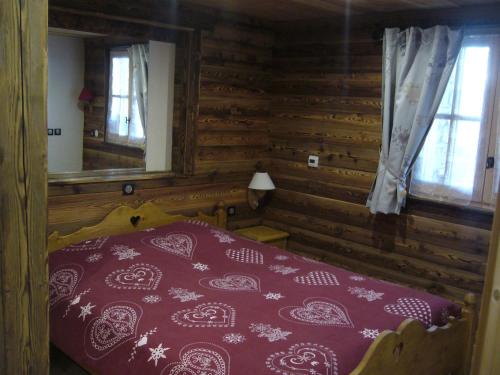 ein Schlafzimmer mit einem Bett in einem Blockhaus in der Unterkunft Chalet la Tuilière***** in Bonneval-sur-Arc