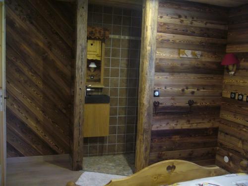 La salle de bains est pourvue de murs en bois et d'une baignoire. dans l'établissement Chalet la Tuilière*****, à Bonneval-sur-Arc