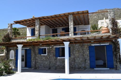 dom z niebieskimi drzwiami i kamienną ścianą w obiekcie Villa Irini w mieście Panormos Mykonos