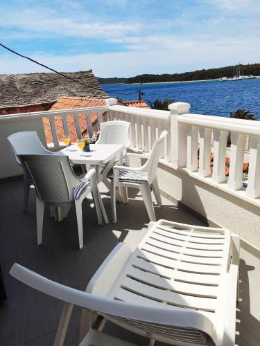 a balcony with white tables and chairs and the water at Apartman Marina II in Rogoznica