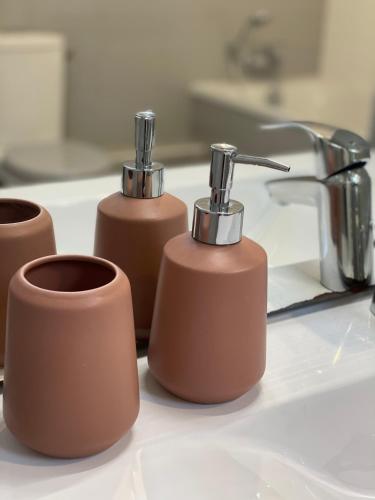 un groupe de trois distributeurs de savon assis sur un évier dans l'établissement La Gervaiserie - 300m de la plage, à Réville