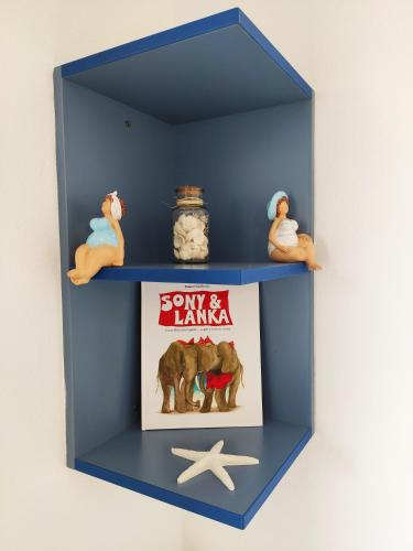 a blue shelf with a book and figurines on it at Apartman Marina II in Rogoznica