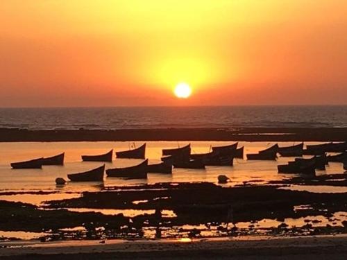 a sunset over the ocean with boats in the water at Appartement Maroc Safi in Safi