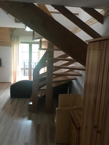 uma sala de estar com uma escada de madeira num quarto em Pensjonat Janus em Ruciane-Nida