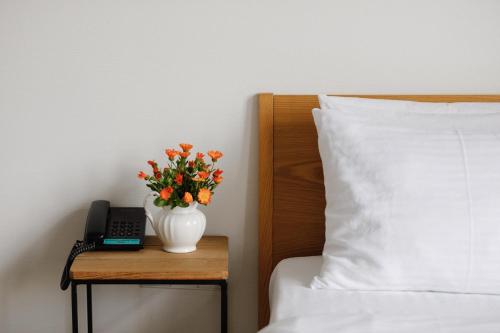 a vase with flowers on a table next to a bed at Mariinsky Boutique Hotel in Batumi