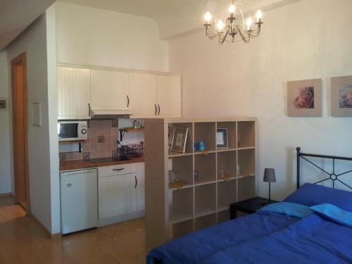 a bedroom with a bed and a kitchen with white cabinets at Studio Ian 1 in Ljubljana