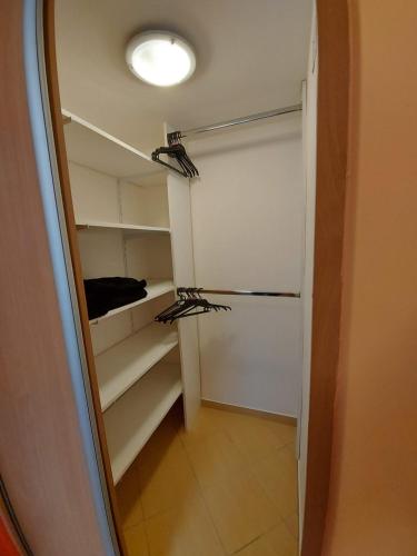 a walk in closet with shelves and a light at Nóra Apartman in Balatonlelle