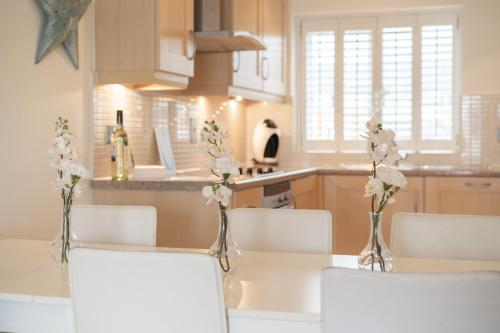 a kitchen with a table with white flowers in vases at LUXURY BEACHFRONT OUTSTANDING 2 bedroom APARTMENT in Eastbourne