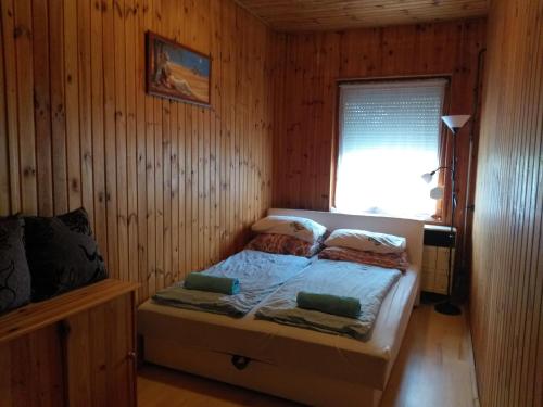 a bedroom with a bed in a wooden room at Tavasz Nyaraló in Poroszló
