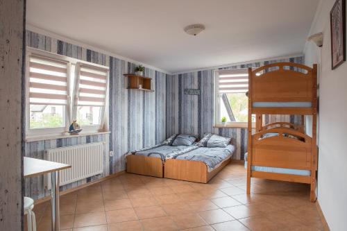 a bedroom with a bunk bed and two windows at Pokoje Emilia I Julia in Łeba