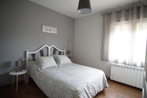 a white bedroom with a bed and a window at La Casa Del Rio in Granja Llumes