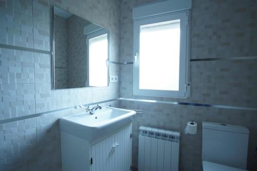 a bathroom with a sink and a mirror and a toilet at La Casa Del Rio in Granja Llumes