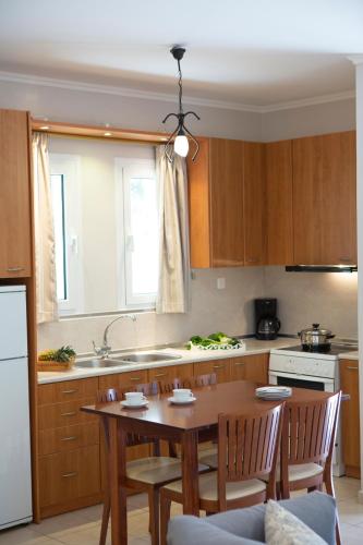 a kitchen with a wooden table with chairs and a sink at Evridiki's Villas in Agios Nikitas