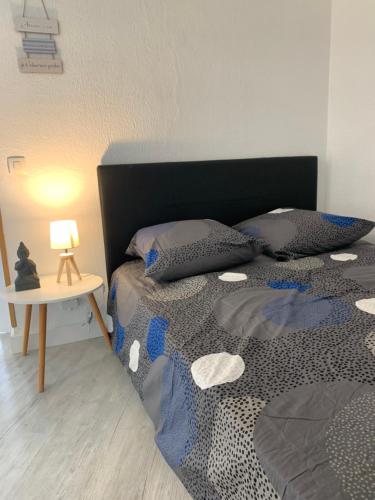 een slaapkamer met een bed en een tafel met een lamp bij Appartement aux 3 Rivieres a Mandelieu in Mandelieu-la-Napoule