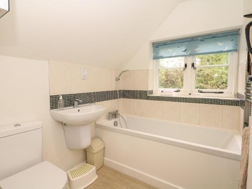 a bathroom with a sink and a tub and a toilet at Marles Farmhouse in Netherbury