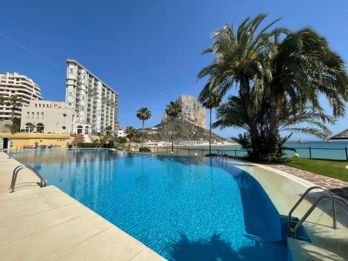 a large swimming pool with palm trees and the ocean at CLP- Primera linea vistas piscina y parking in Calpe