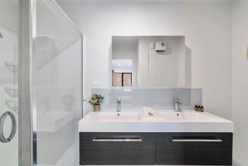 een witte badkamer met een wastafel en een douche bij Alpine Loft with Jaw-dropping View! in Queenstown