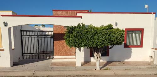 a white house with a gate and a tree at Casa Villa Serena 8 in San Carlos